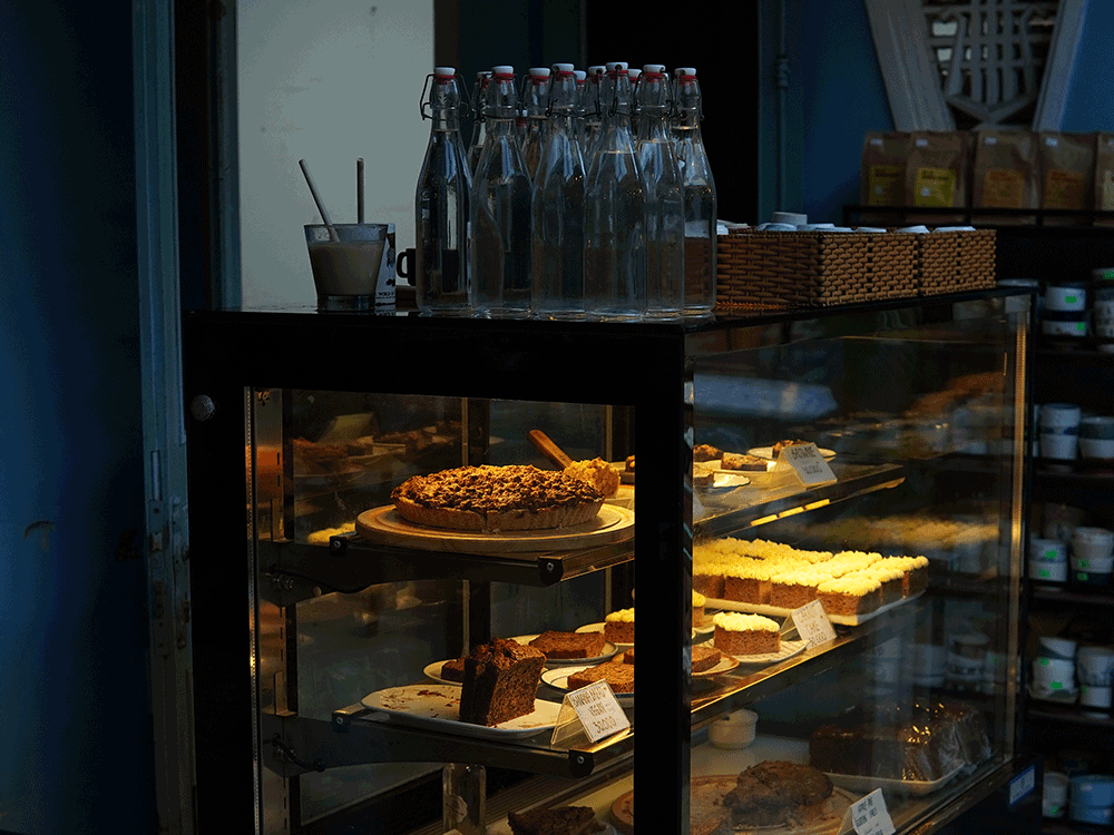 An assortment of freshly bake desserts including brownies, apple pie, and carrot cake, all beautifully lit with warm tones in a quaint Hoi An café