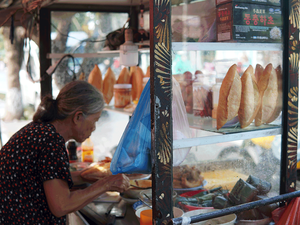 In the street of Hoi An, an elderly lady skillfully prepares the signature banh mi, one of the most famlous Hoi An food.