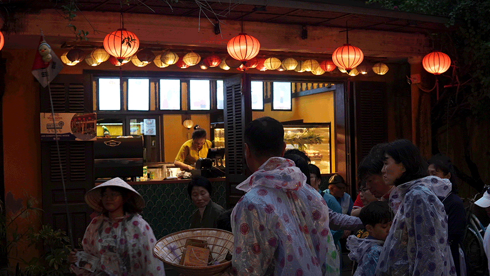 Rainy evening in Hoi An Old Town, with a traveler wandering through the wet streets, illuminated by colorful lanterns.